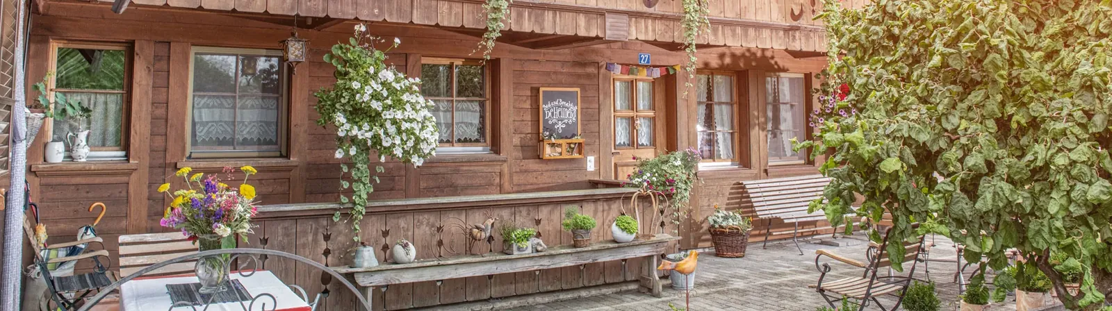 Das Holzhaus des BnB DeHeimelig mit Sitzplatz und Blumen
